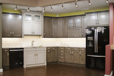 Inspiration for a mid-sized transitional l-shaped dark wood floor eat-in kitchen remodel in Other with an undermount sink, gray cabinets, white backsplash, subway tile backsplash, black appliances, no island, recessed-panel cabinets and granite countertops