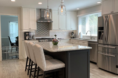 This is an example of a mid-sized transitional l-shaped open plan kitchen in DC Metro with an undermount sink, flat-panel cabinets, white cabinets, granite benchtops, white splashback, porcelain splashback, stainless steel appliances, porcelain floors, with island, brown floor and white benchtop.
