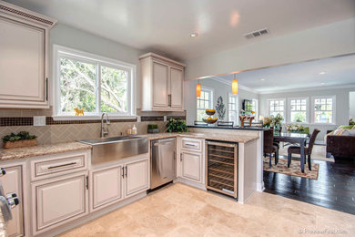 Inspiration for a beach style u-shaped kitchen in Orange County with a farmhouse sink, white cabinets, granite benchtops, stainless steel appliances, ceramic floors and no island.