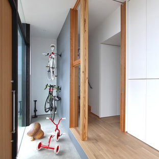 他の地域のモダンスタイルのおしゃれな玄関ラウンジ (白い壁、コンクリートの床、木目調のドア) の写真