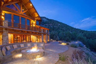 Inspiration for a large country backyard patio in Denver with a fire feature, natural stone pavers and no cover.