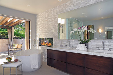 Design ideas for a mid-sized contemporary master bathroom in Los Angeles with flat-panel cabinets, dark wood cabinets, marble benchtops, gray tile, porcelain tile, a freestanding tub, a corner shower, a one-piece toilet, an undermount sink, grey walls and porcelain floors.