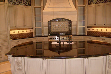Eat-in kitchen - large traditional u-shaped ceramic tile eat-in kitchen idea in Houston with marble countertops, beige backsplash, porcelain backsplash, an island, an undermount sink, raised-panel cabinets, white cabinets and paneled appliances