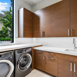 マイアミの大きいコンテンポラリースタイルのおしゃれな洗濯室 (アンダーカウンターシンク、フラットパネル扉のキャビネット、中間色木目調キャビネット、白い壁、大理石の床、左右配置の洗濯機・乾燥機、白い床、白いキッチンカウンター) の写真