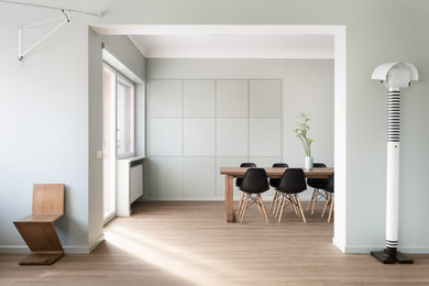 This is an example of a contemporary open plan dining in Rome with green walls, light hardwood floors and no fireplace.