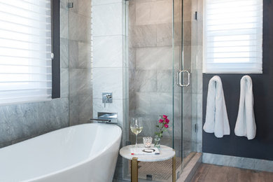 Design ideas for a mid-sized transitional master bathroom in Denver with a hinged shower door, a freestanding tub, an open shower, gray tile, marble, black walls, porcelain floors, marble benchtops, grey floor and grey benchtops.