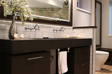Photo of a large transitional master bathroom in Minneapolis with flat-panel cabinets, dark wood cabinets, a freestanding tub, an alcove shower, a one-piece toilet, white tile, ceramic tile, beige walls, light hardwood floors, a trough sink, beige floor and a hinged shower door.