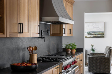 Large mountain style galley medium tone wood floor enclosed kitchen photo in DC Metro with recessed-panel cabinets, medium tone wood cabinets, quartz countertops, black backsplash, quartz backsplash, stainless steel appliances, no island and black countertops