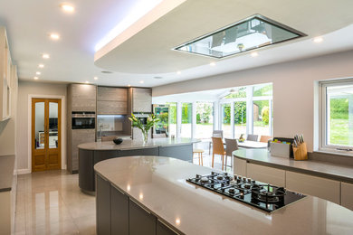 Inspiration for a large modern kitchen/diner in Surrey with quartz worktops, grey splashback, multiple islands and beige floors.