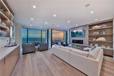 Inspiration for a large contemporary open concept and formal light wood floor and brown floor living room remodel in Los Angeles with gray walls, a ribbon fireplace, a wall-mounted tv and a plaster fireplace