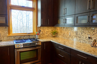Example of a mid-sized trendy u-shaped medium tone wood floor eat-in kitchen design in Charlotte with flat-panel cabinets, dark wood cabinets, granite countertops, multicolored backsplash, stone slab backsplash, stainless steel appliances, no island and a single-bowl sink