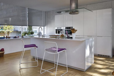 Diseño de cocina moderna con puertas de armario blancas, encimera de cuarzo compacto y una isla