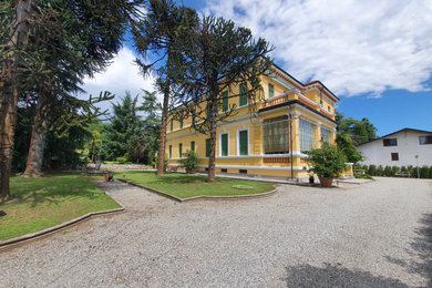 Immagine della facciata di una casa bifamiliare ampia gialla classica a due piani con rivestimenti misti