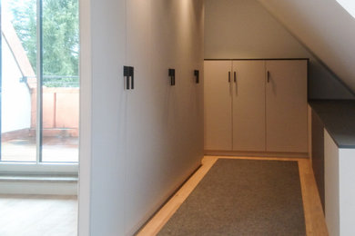 Mittelgroßer Moderner Begehbarer Kleiderschrank mit flächenbündigen Schrankfronten, grauen Schränken, hellem Holzboden und beigem Boden in München