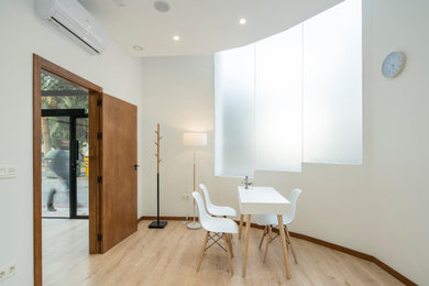 Modelo de despacho mediterráneo de tamaño medio con paredes blancas, suelo de madera clara y escritorio independiente