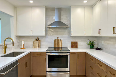 Mid-sized trendy u-shaped laminate floor and brown floor kitchen pantry photo in San Diego with an undermount sink, flat-panel cabinets, light wood cabinets, quartz countertops, white backsplash, ceramic backsplash, stainless steel appliances, a peninsula and white countertops