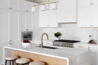 Example of a mid-sized transitional l-shaped light wood floor and brown floor eat-in kitchen design in Los Angeles with an undermount sink, shaker cabinets, white cabinets, quartz countertops, white backsplash, ceramic backsplash, stainless steel appliances, an island and multicolored countertops