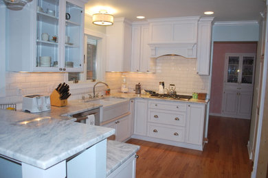 Inspiration for a large cottage u-shaped medium tone wood floor kitchen pantry remodel in Milwaukee with a farmhouse sink, recessed-panel cabinets, white cabinets, granite countertops, white backsplash, ceramic backsplash, stainless steel appliances and a peninsula