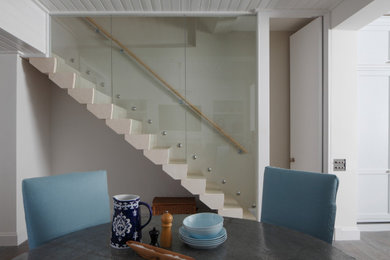 Ejemplo de escalera recta actual con escalones de piedra caliza, contrahuellas de piedra caliza y barandilla de vidrio