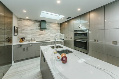 Inspiration for a large contemporary u-shaped porcelain tile and white floor eat-in kitchen remodel in Tampa with an undermount sink, flat-panel cabinets, gray cabinets, quartzite countertops, beige backsplash, stone tile backsplash, stainless steel appliances, an island and white countertops