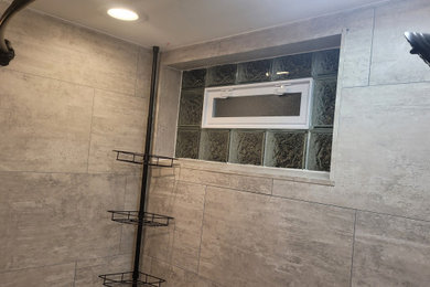 ミルウォーキーにある低価格の小さなトラディショナルスタイルのおしゃれな浴室 (シャワー付き浴槽	、グレーの壁、ラミネートの床) の写真