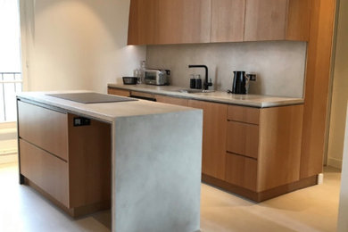 Exemple d'une cuisine ouverte parallèle et encastrable moderne de taille moyenne avec un placard à porte plane, un plan de travail en béton, une crédence grise, sol en béton ciré, îlot, un sol gris et un plan de travail gris.