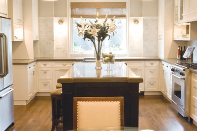 Kitchen - medium tone wood floor kitchen idea in Calgary with white cabinets, stainless steel appliances and an island