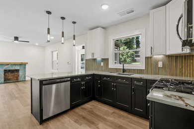 Open concept kitchen - mid-sized u-shaped vinyl floor and brown floor open concept kitchen idea in Atlanta with a single-bowl sink, shaker cabinets, black cabinets, quartzite countertops, brown backsplash, ceramic backsplash, stainless steel appliances, gray countertops and a peninsula