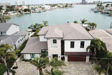 Large contemporary white two-story stucco house exterior idea in Tampa with a hip roof and a shingle roof