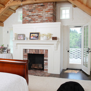 This is an example of a large country master bedroom in Boston with white walls, carpet, a standard fireplace, a brick fireplace surround and beige floor.