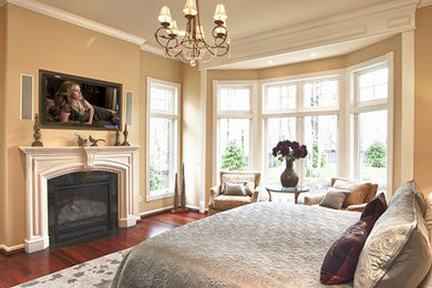 Inspiration for a mid-sized transitional master bedroom in Cleveland with beige walls, medium hardwood floors, a standard fireplace, a stone fireplace surround and brown floor.