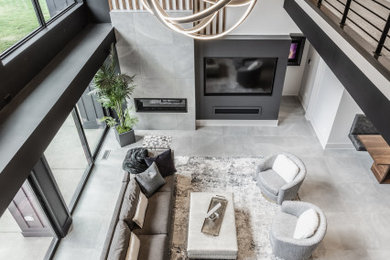 Example of a trendy open concept porcelain tile, gray floor and wood wall living room design in Indianapolis with black walls, a tile fireplace and a media wall