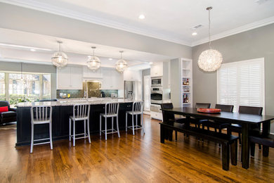 Mid-sized trendy medium tone wood floor eat-in kitchen photo in Dallas with a farmhouse sink, shaker cabinets, white cabinets, granite countertops, green backsplash, glass tile backsplash and stainless steel appliances
