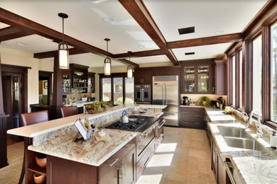 This is an example of a mid-sized arts and crafts l-shaped eat-in kitchen in Sacramento with an undermount sink, shaker cabinets, dark wood cabinets, granite benchtops, stainless steel appliances, travertine floors, with island, brown floor and grey benchtop.