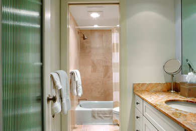 Small trendy stone tile and brown tile marble floor bathroom photo in Tampa with an undermount sink, recessed-panel cabinets, white cabinets, marble countertops, a one-piece toilet and beige walls