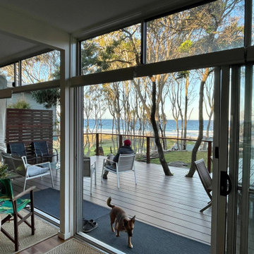 view looking out form living across deck & towards water