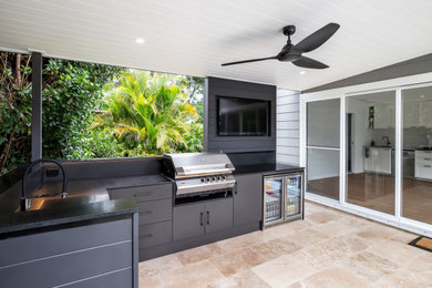 Photo of a mid-sized contemporary backyard patio in Sydney with an outdoor kitchen, natural stone pavers and a roof extension.