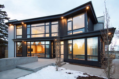 Modelo de fachada de casa negra minimalista de tamaño medio de dos plantas con revestimiento de madera