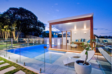 Mid-sized modern backyard custom-shaped aboveground pool in Brisbane with a pool house and natural stone pavers.