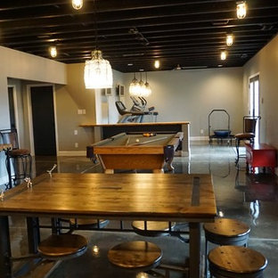 This is an example of a large modern walk-out basement in Louisville with grey walls and concrete flooring.