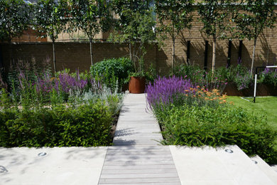 Photo of a mid-sized contemporary backyard full sun formal garden in London with with flowerbed and decking.