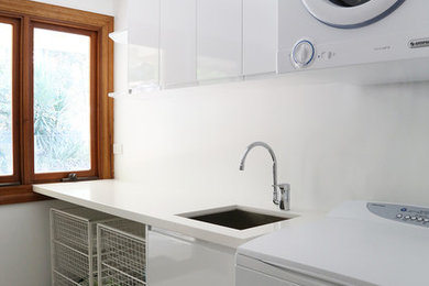 This is an example of a mid-sized contemporary single-wall dedicated laundry room in Brisbane with an undermount sink, flat-panel cabinets, white cabinets and white benchtop.