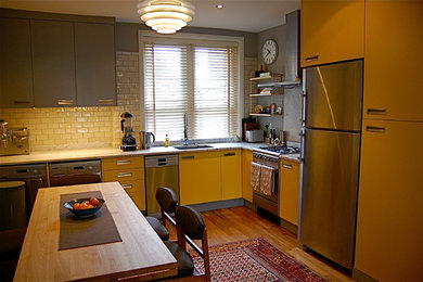 Design ideas for a large contemporary l-shaped eat-in kitchen in London with an undermount sink, flat-panel cabinets, yellow cabinets, quartz benchtops, white splashback, subway tile splashback, stainless steel appliances, medium hardwood floors and no island.