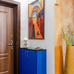 Inredning av en eklektisk ingång och ytterdörr, med vita väggar, en enkeldörr, mellanmörk trädörr och blått golv