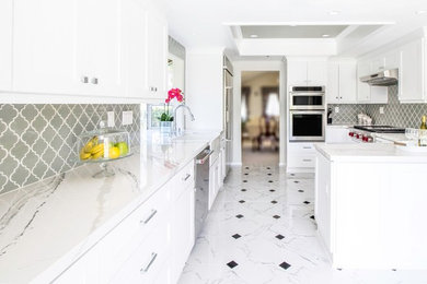 Minimalist porcelain tile kitchen photo in Los Angeles with a farmhouse sink, gray backsplash, glass tile backsplash and stainless steel appliances