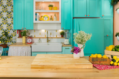 Example of a mid-sized farmhouse galley enclosed kitchen design in New York with a farmhouse sink, recessed-panel cabinets, turquoise cabinets, wood countertops, white backsplash, subway tile backsplash, colored appliances and a peninsula