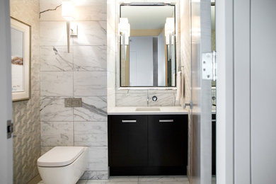 Inspiration for a mid-sized modern powder room in Vancouver with flat-panel cabinets, black cabinets, a wall-mount toilet, white tile, marble, grey walls, marble floors, an undermount sink, engineered quartz benchtops, white floor and white benchtops.