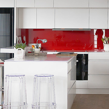 die roten Glasrückwände sorgen für den Farbtupfer in der weißen Küche