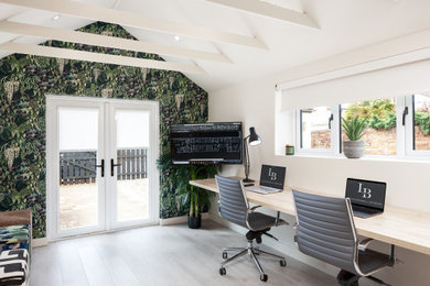 Inspiration for a large contemporary study in Other with beige walls, light hardwood flooring, a built-in desk and beige floors.