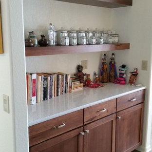 Cette photo montre une grande arrière-cuisine moderne avec un évier encastré, un placard à porte shaker, des portes de placard en bois brun, une crédence blanche, un électroménager blanc, un sol en bois brun, une péninsule et un plan de travail en verre recyclé.